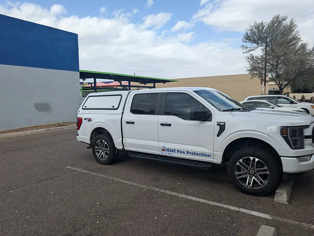 White Ford truck parked in a parking lot, with other vehicles visible in the background.