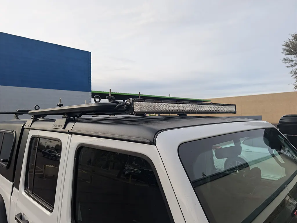 White vehicle with a roof-mounted light bar and rack system parked at Canyon State.