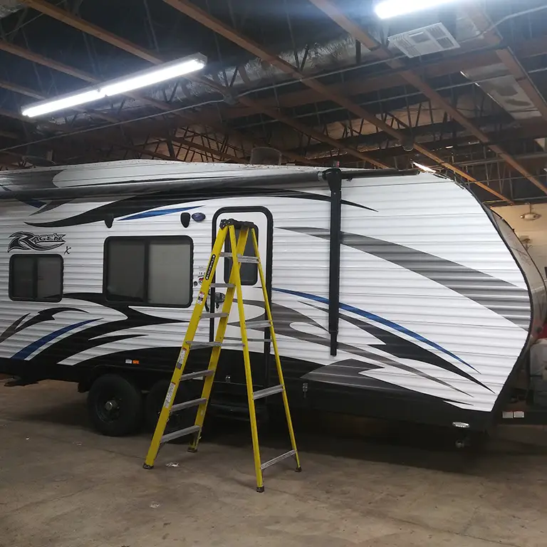 RV undergoing repair, with focus on exterior work being done.