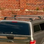 Roof rack from Canyon State installed on a Ford truck bed cap, displayed against a brick wall.