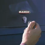 Hand unlocking a "Ranch" truck bed cap from Canyon State with a key on the tailgate.
