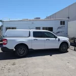 White Ford truck with a Ranch Echo camper shell parked outside Canyon State RV.