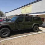 Green Jeep Gladiator with a Ranch Echo camper shell parked outside Canyon State RV.