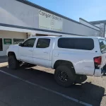 White Toyota Tacoma with a Ranch Echo camper shell parked outside Canyon State RV.