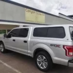 Silver Ford F-150 STX with a Ranch Echo camper shell parked outside Canyon State RV.