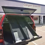 Red truck with a Ranch Echo camper shell and Cap-Pack storage system outside Canyon State RV.