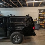 Black truck with a Ranch Echo camper shell inside a workshop at Canyon State RV.