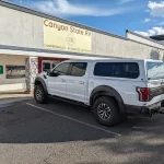 White Ford truck with a Ranch Echo camper shell parked outside Canyon State RV.