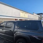 Black Toyota Tacoma with a Ranch Echo camper shell parked outside Canyon State RV.