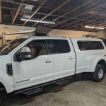 White Ford F-350 with a Ranch Echo camper shell inside Canyon State RV's workshop.