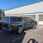Black Toyota Tacoma with a Ranch Echo camper shell parked outside Canyon State RV.