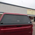 Red Chevrolet RST with a Ranch Echo camper shell parked outside Canyon State RV.