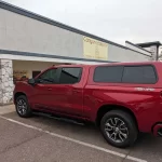 Red Chevrolet 4x4 with a Ranch Echo camper shell parked outside Canyon State RV.