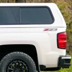 White truck with a "Ranch Echo" truck bed cap from Canyon State, showing a side window.