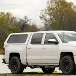 White Chevrolet Silverado with a "Ranch Echo" truck bed cap from Canyon State parked outdoors.