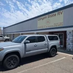 Silver Toyota Tacoma with a Ranch Echo camper shell outside Canyon State RV.