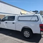 White Ford Super Duty with a Ranch Echo camper shell outside Canyon State RV.