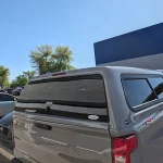 Gray Chevrolet Silverado with a Ranch Fusion camper shell from Canyon State RV, parked in a lot.