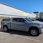 Gray Chevrolet Silverado with a Ranch Fusion camper shell, parked outside Canyon State RV.