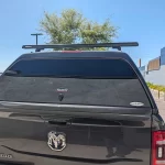 Black Ram Laramie with a Ranch Fusion camper shell and roof rack, parked outside Canyon State RV.
