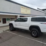 White Toyota Tacoma TRD 4x4 with a Ranch Fusion cap, parked outside Canyon State RV.