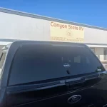 Black Ford with a Ranch Fusion camper shell from Canyon State RV, parked outside the store.
